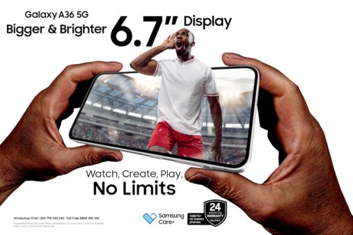 Hands holding a Samsung Galaxy A36 5G smartphone with a football player in red shorts and a white jersey appearing to burst out of the screen inside a stadium, highlighting its 6.7-inch display.