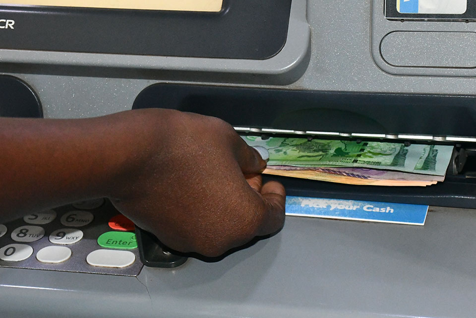 Customers withdraw cash from an ATM, a routine transaction at the center of policy debate after government dropped plans to introduce a tax on all cash withdrawals.